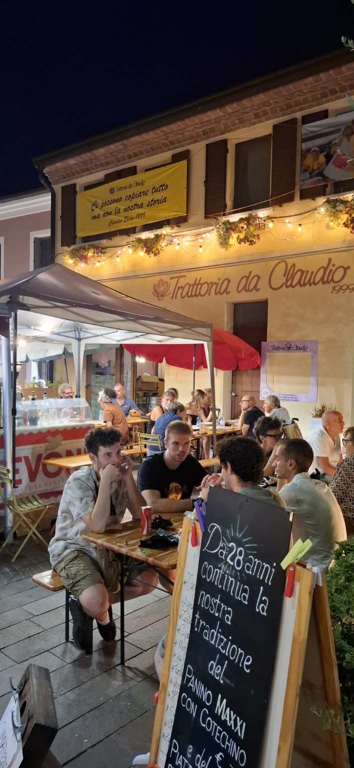 Esterno della Trattoria da Claudio con tavoli e ospiti